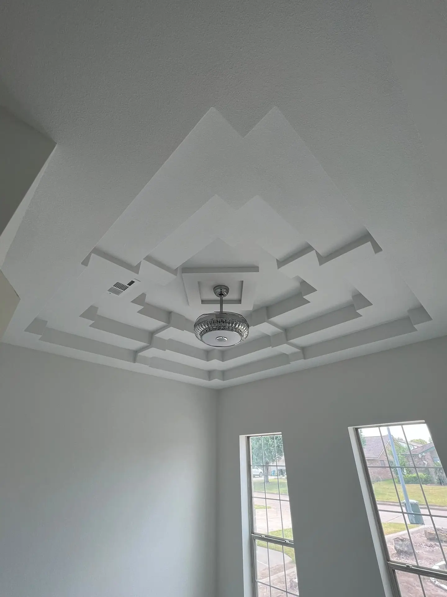 Step tray ceiling finished in drywall around a light fixture