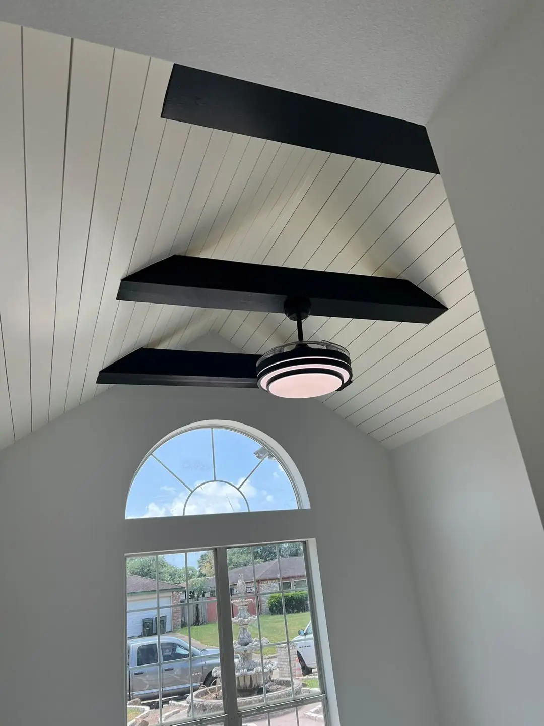 Vaulted shiplap ceiling, black beams, arched window