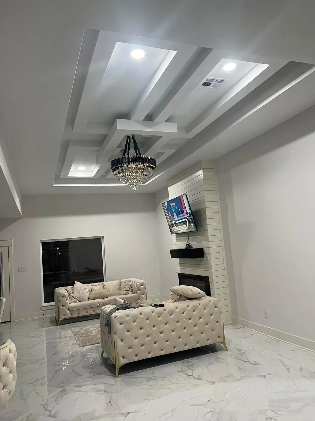 Finished living room: marble floor, tray ceiling, chandelier, TV wall