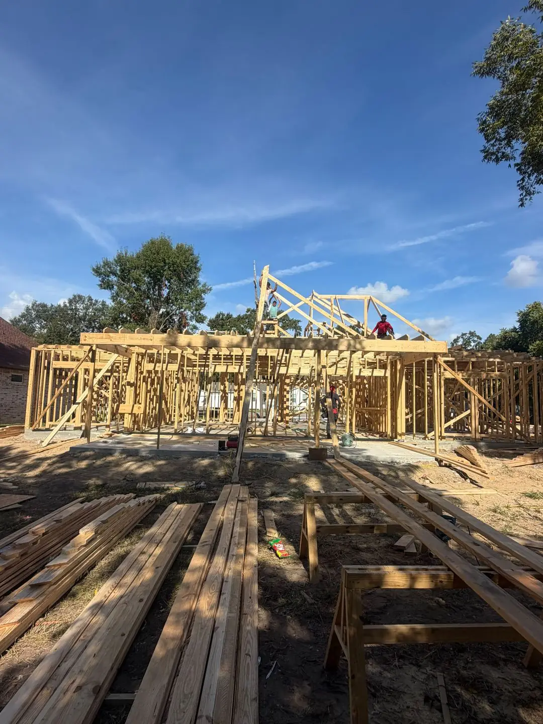 Wood framing + roof trusses going up, Rocha's sign on lot, Groves, TX