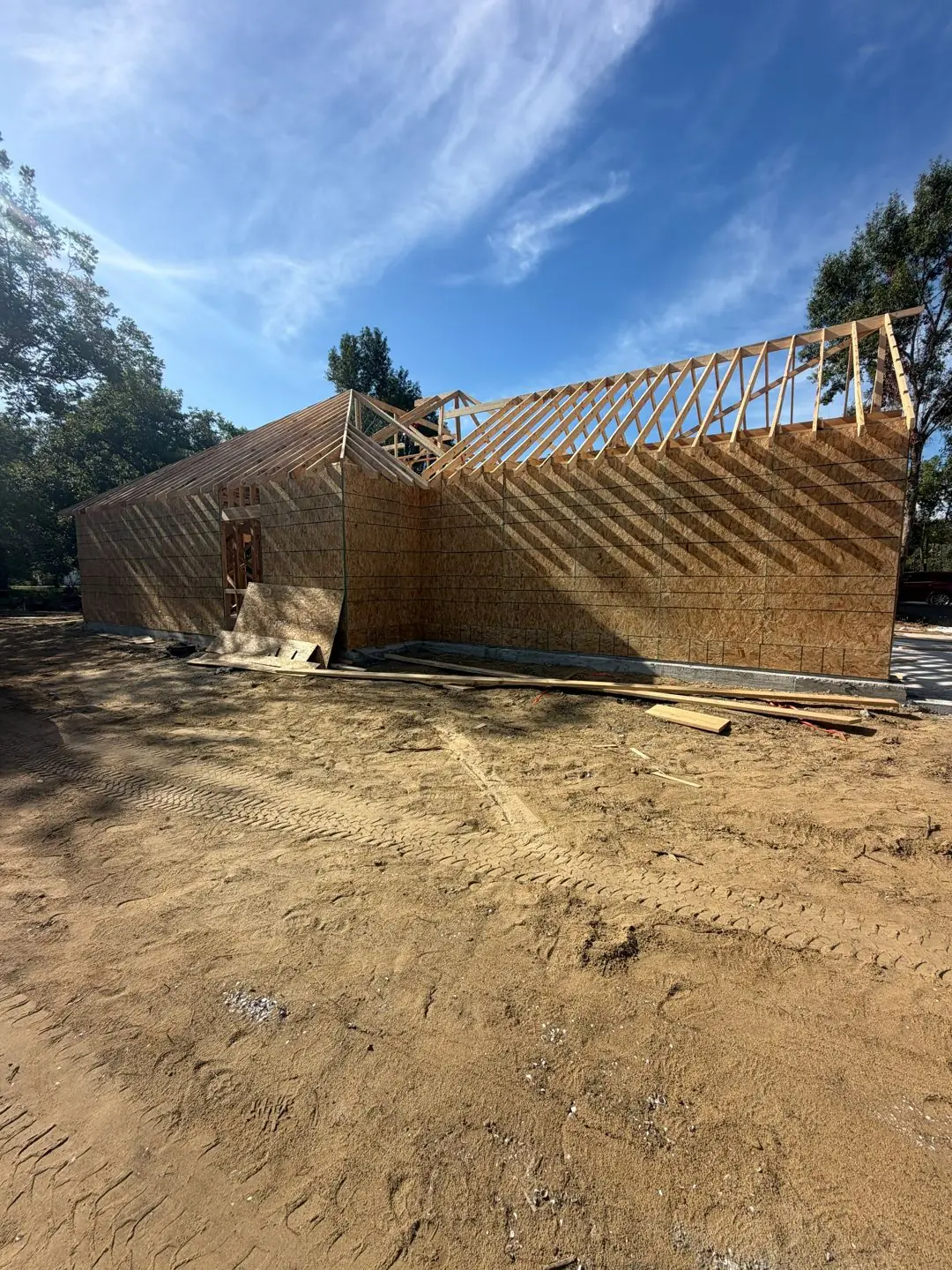 Wood framing + roof trusses going up, Rocha's sign on lot, Groves, TX