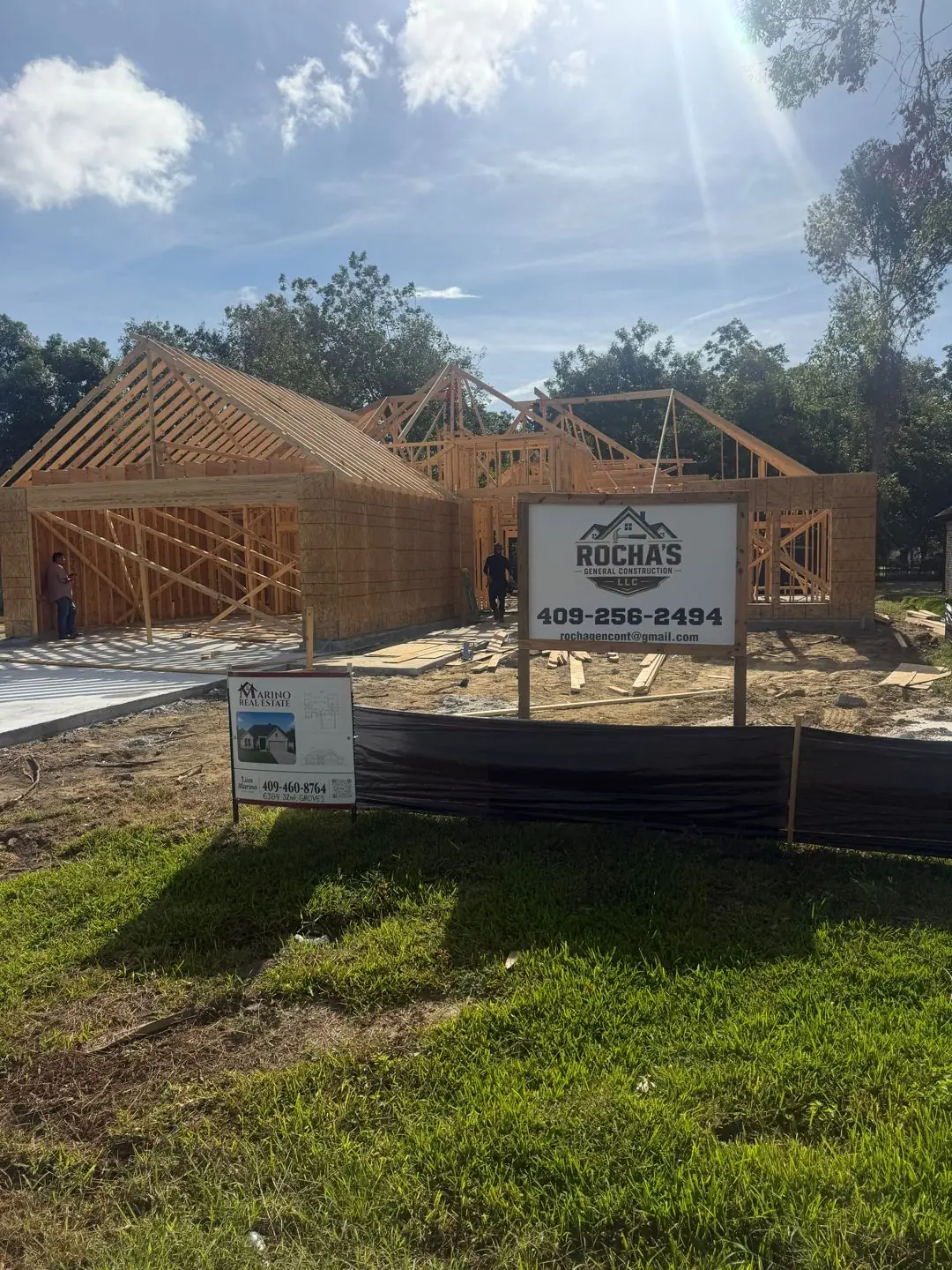 Wood framing + roof trusses going up, Rocha's sign on lot, Groves, TX