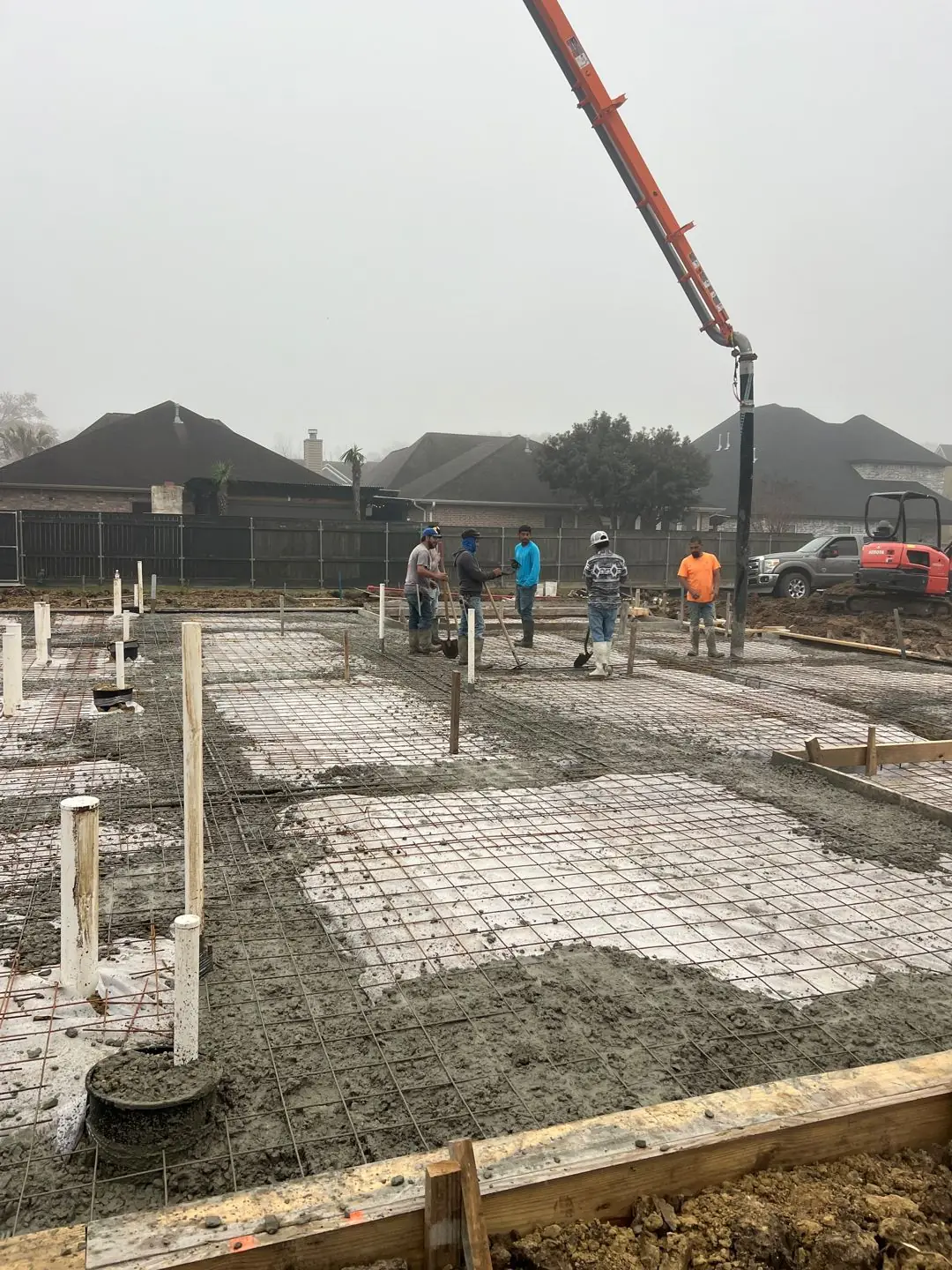 Slab pour with pump truck, rebar mesh, crew in hi-vis
