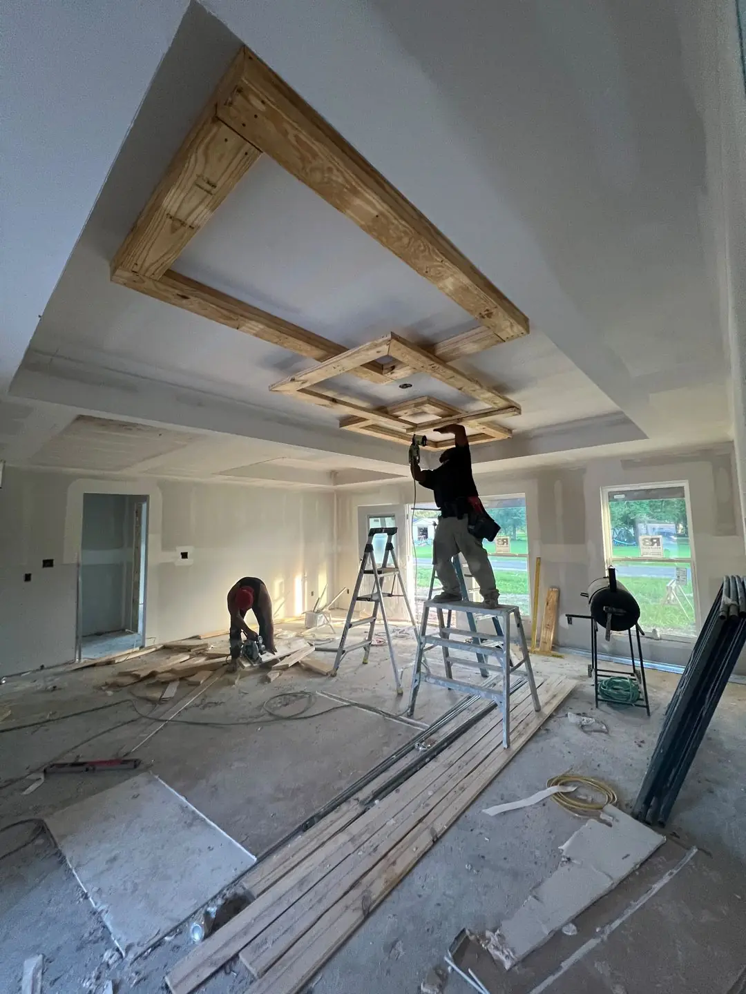 Framing / spray foam / insulation / drywall stages: tray ceilings, scaffold, workers, plumbing PEX manifold, electrical conduit