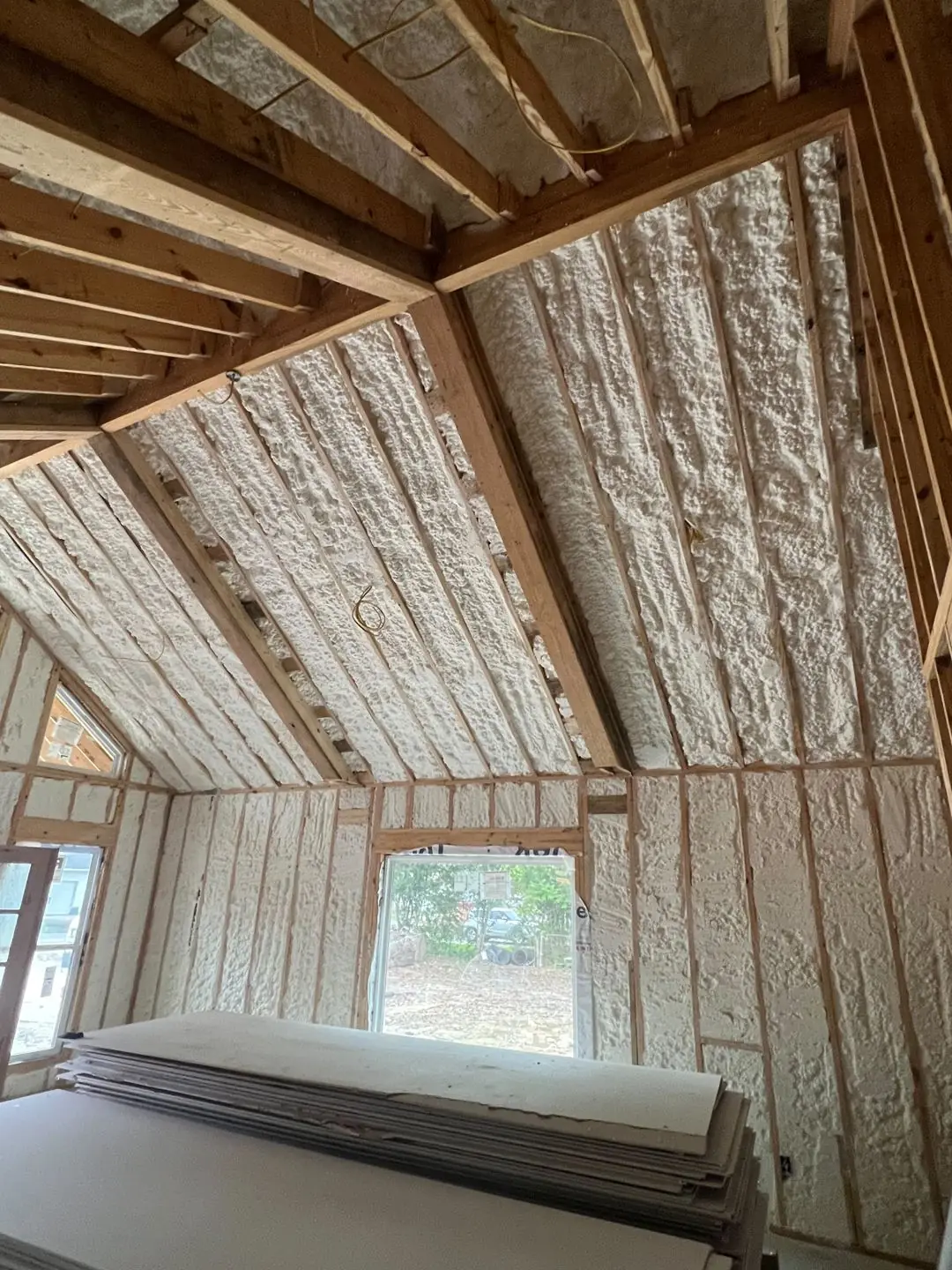 Framing / spray foam / insulation / drywall stages: tray ceilings, scaffold, workers, plumbing PEX manifold, electrical conduit
