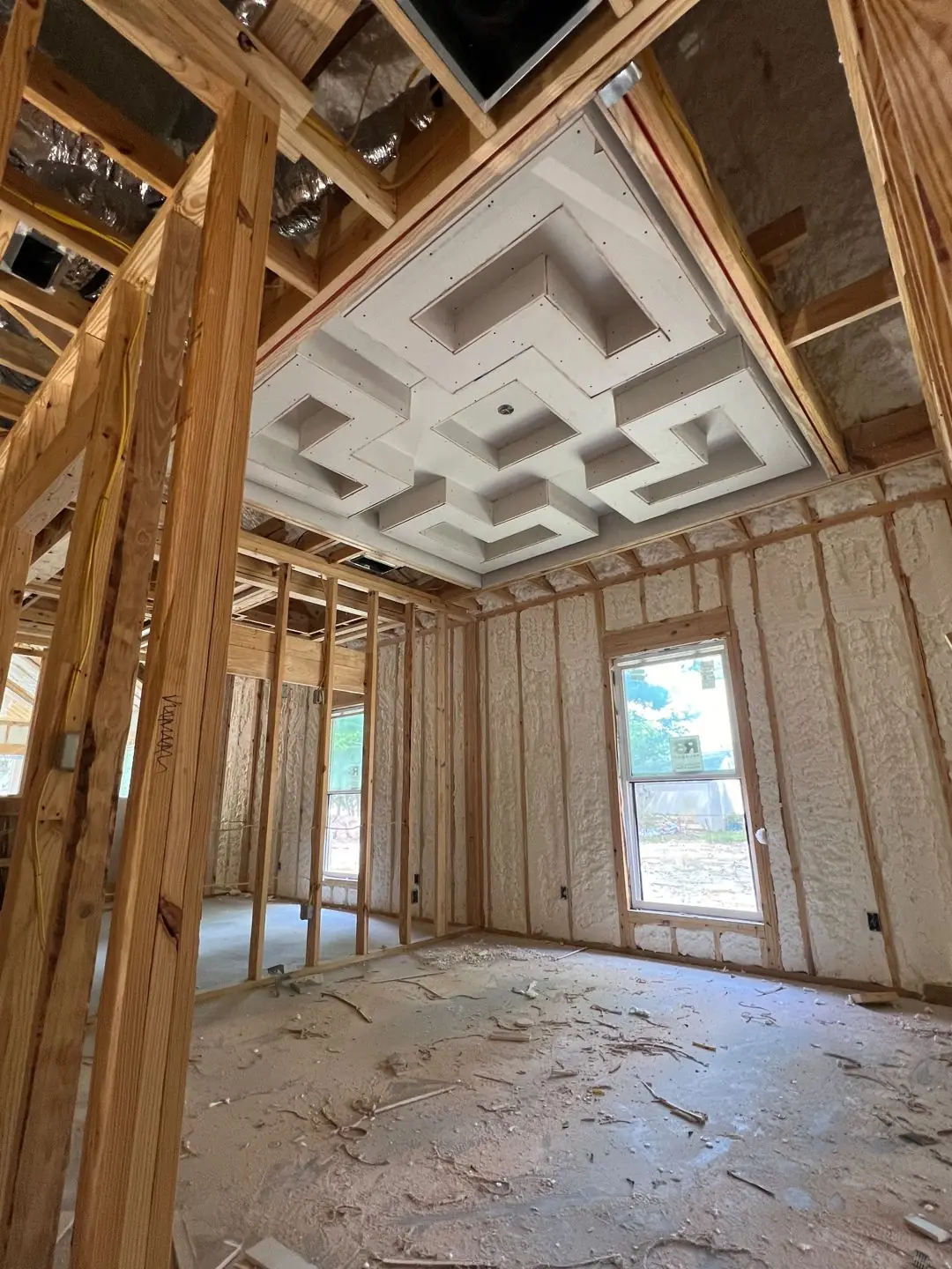 Framing / spray foam / insulation / drywall stages: tray ceilings, scaffold, workers, plumbing PEX manifold, electrical conduit