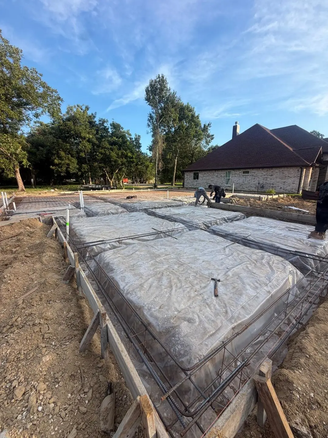Slab forms, rebar, vapor barrier laid, crew prepping