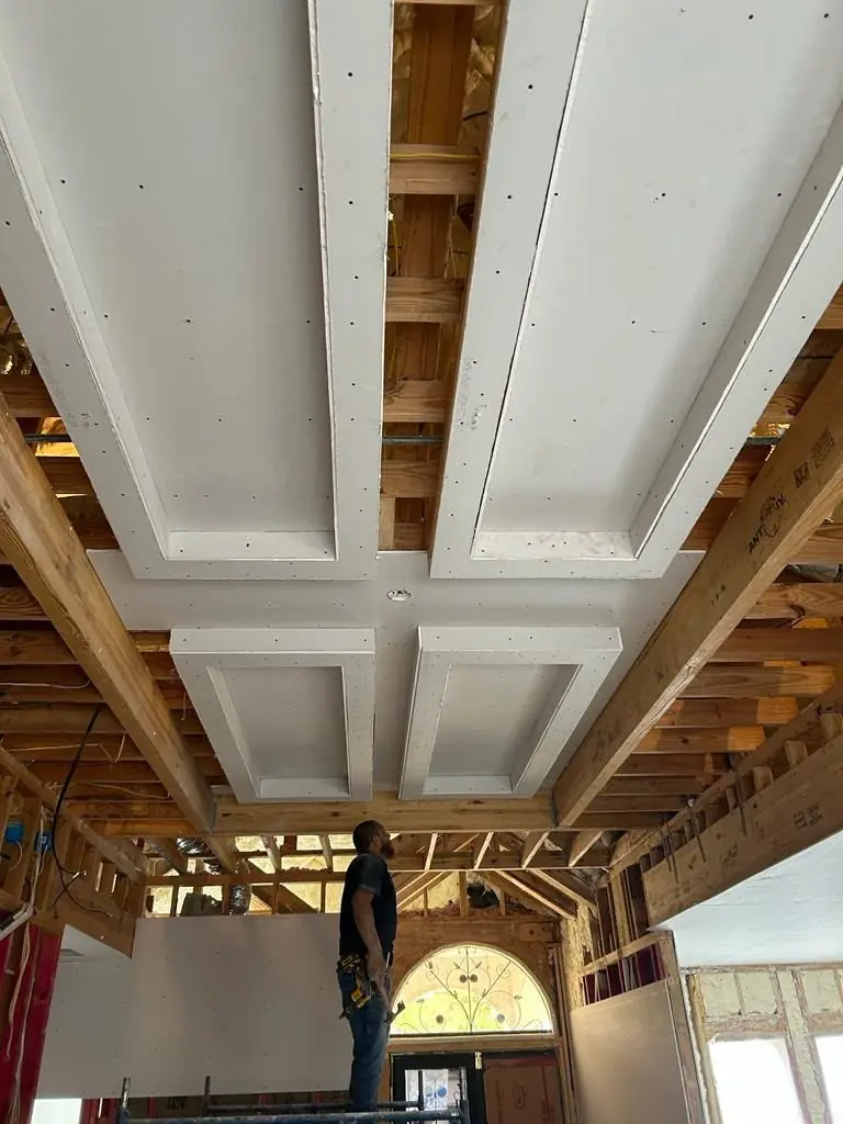 Ceiling framing + drywall coffers w/ worker on scaffold