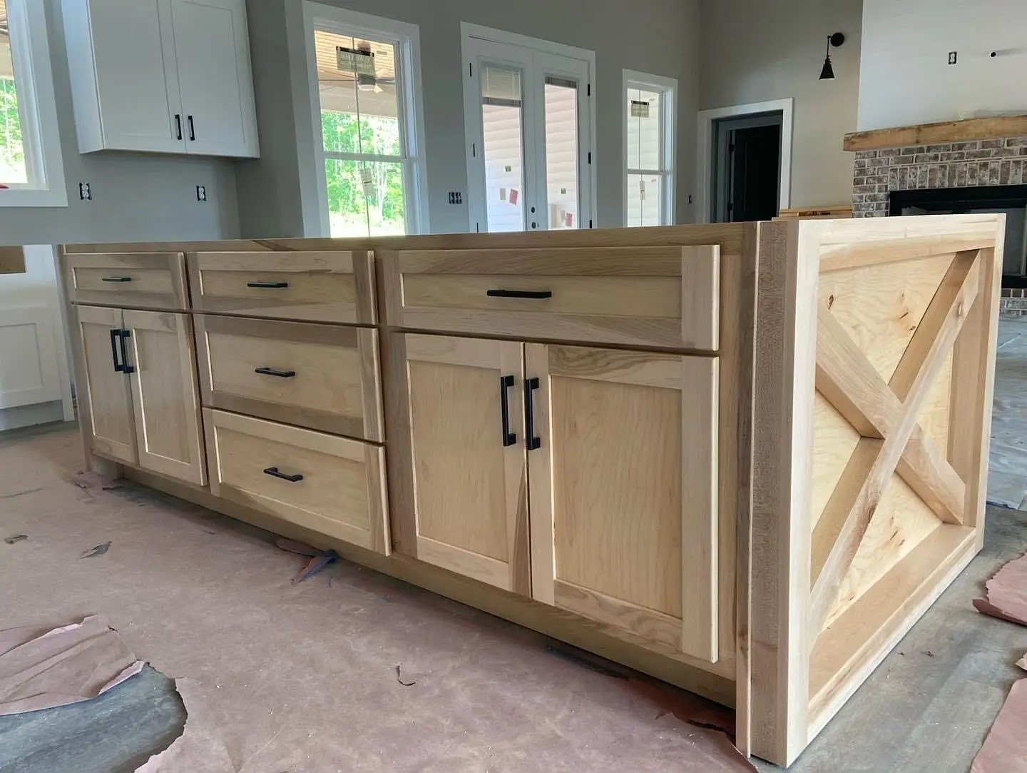 Finished kitchen: white cabinets, X-barn-door island, quartz, pendants, wood range hood