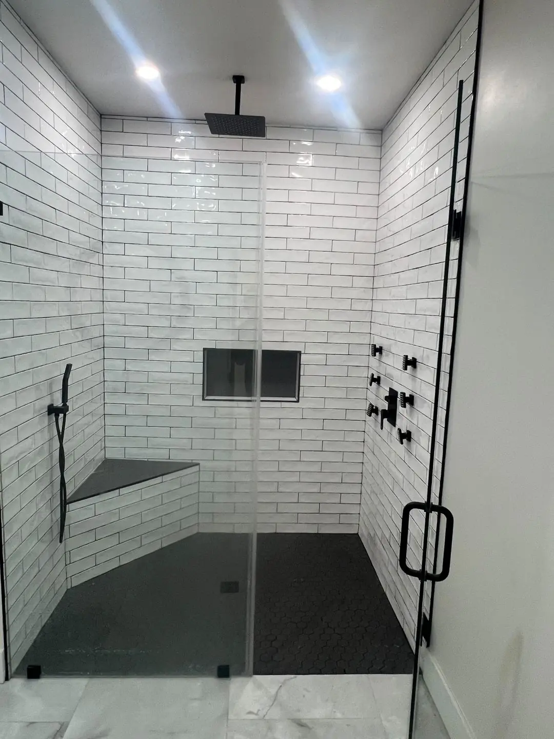 Finished white subway tile shower, black fixtures, glass