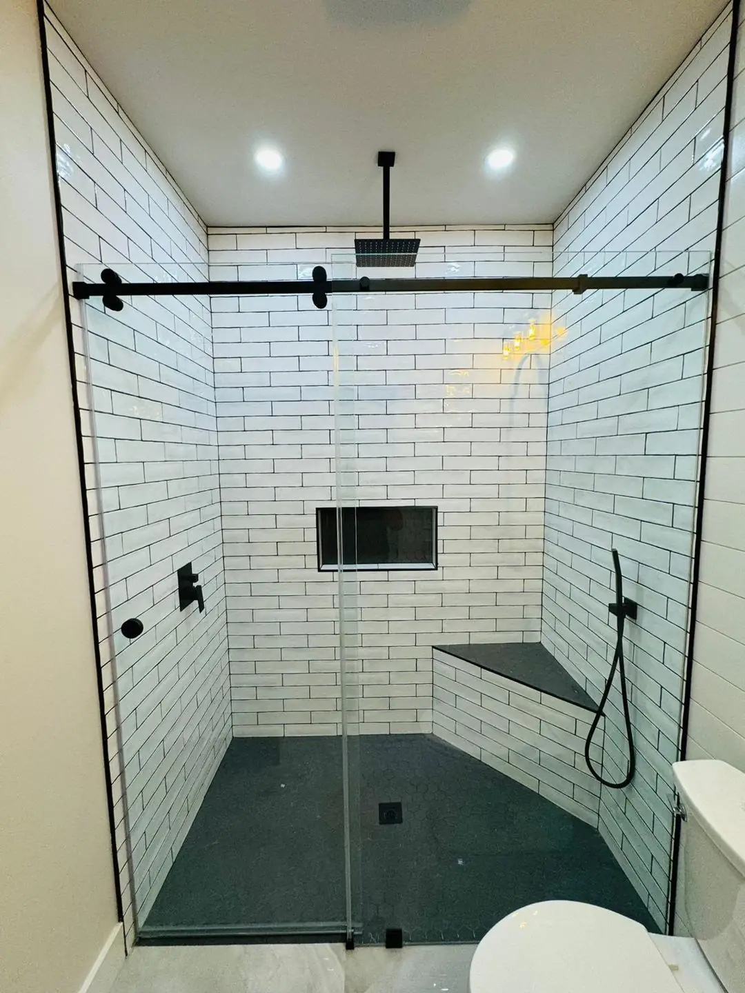 Finished white subway tile shower, black fixtures, glass