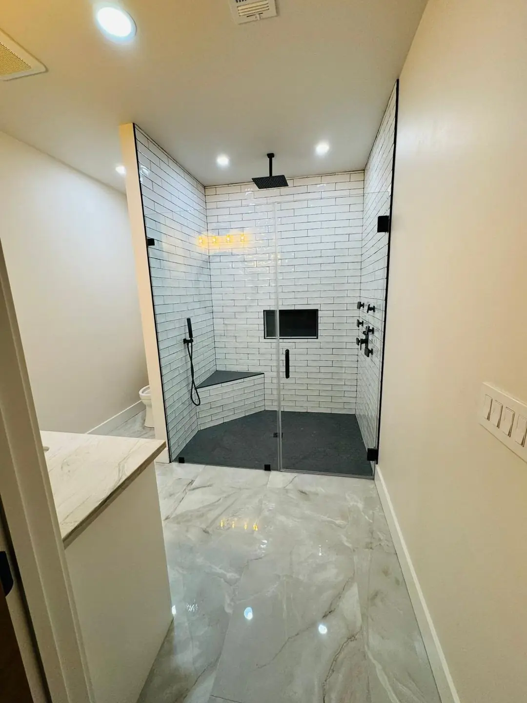 Finished white subway tile shower, black fixtures, glass