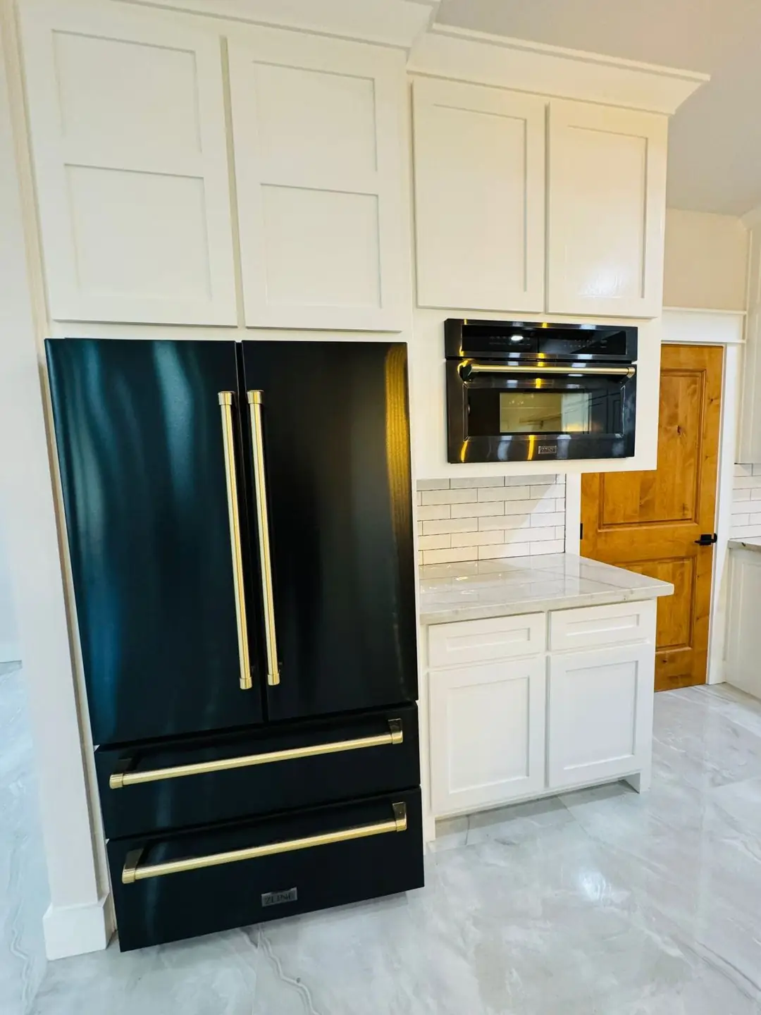 Black fridge, white cabinets, marble counter