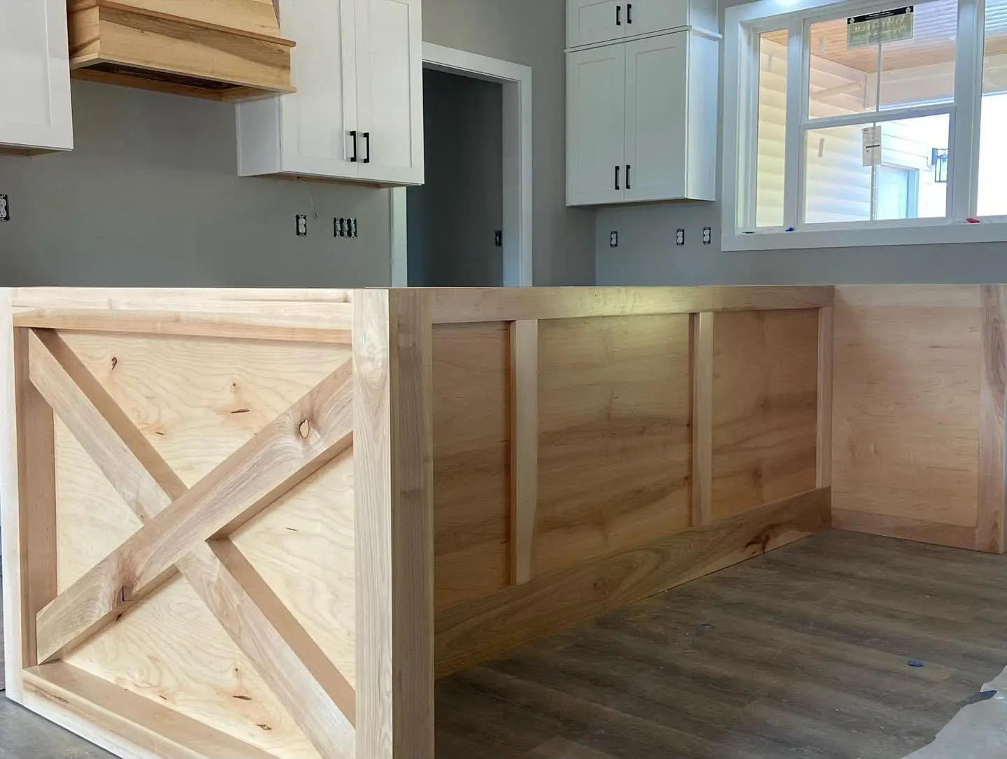 Finished kitchen: white cabinets, X-barn-door island, quartz, pendants, wood range hood