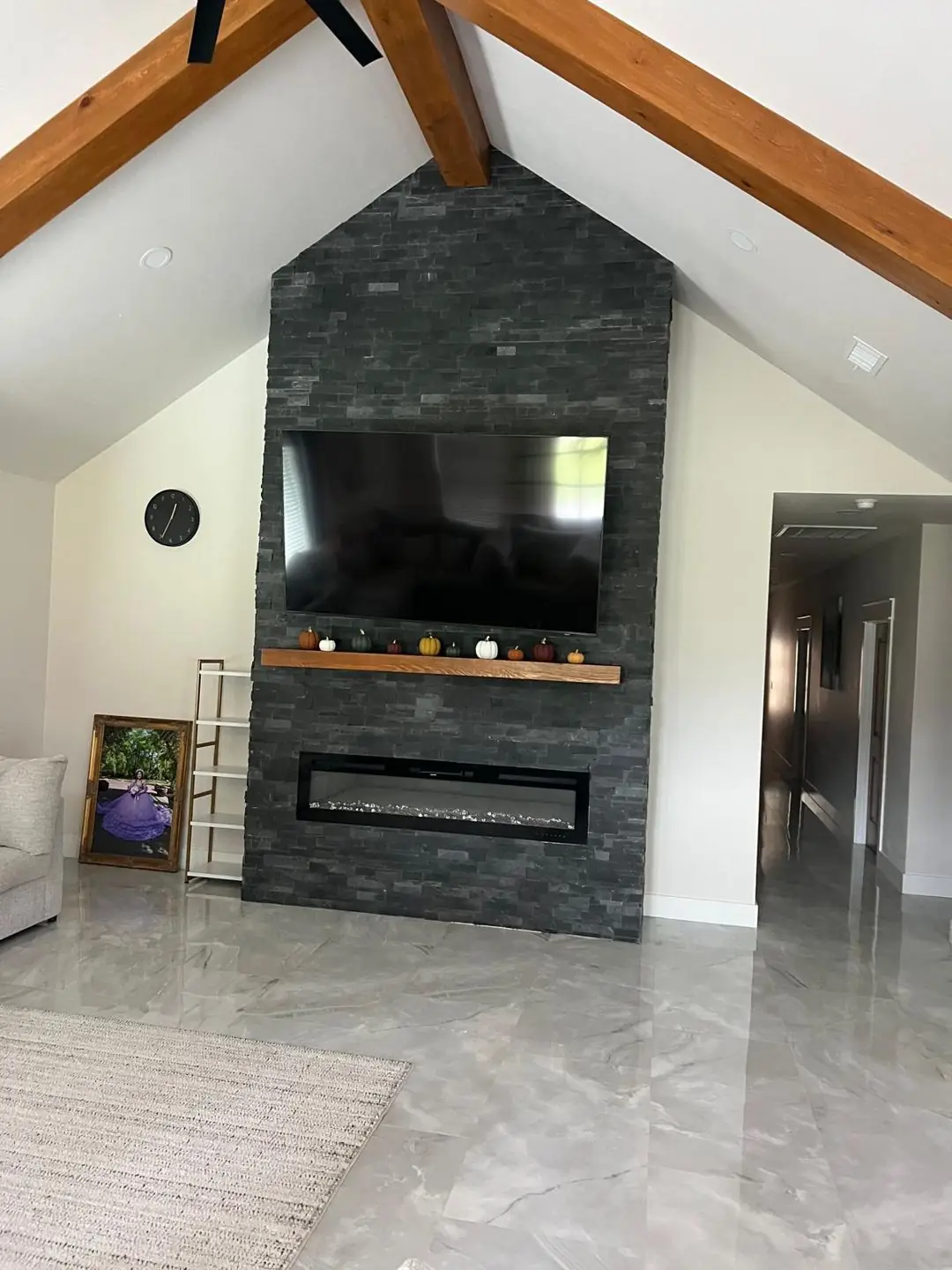 Finished living: dark stone fireplace wall, vaulted beams, TV