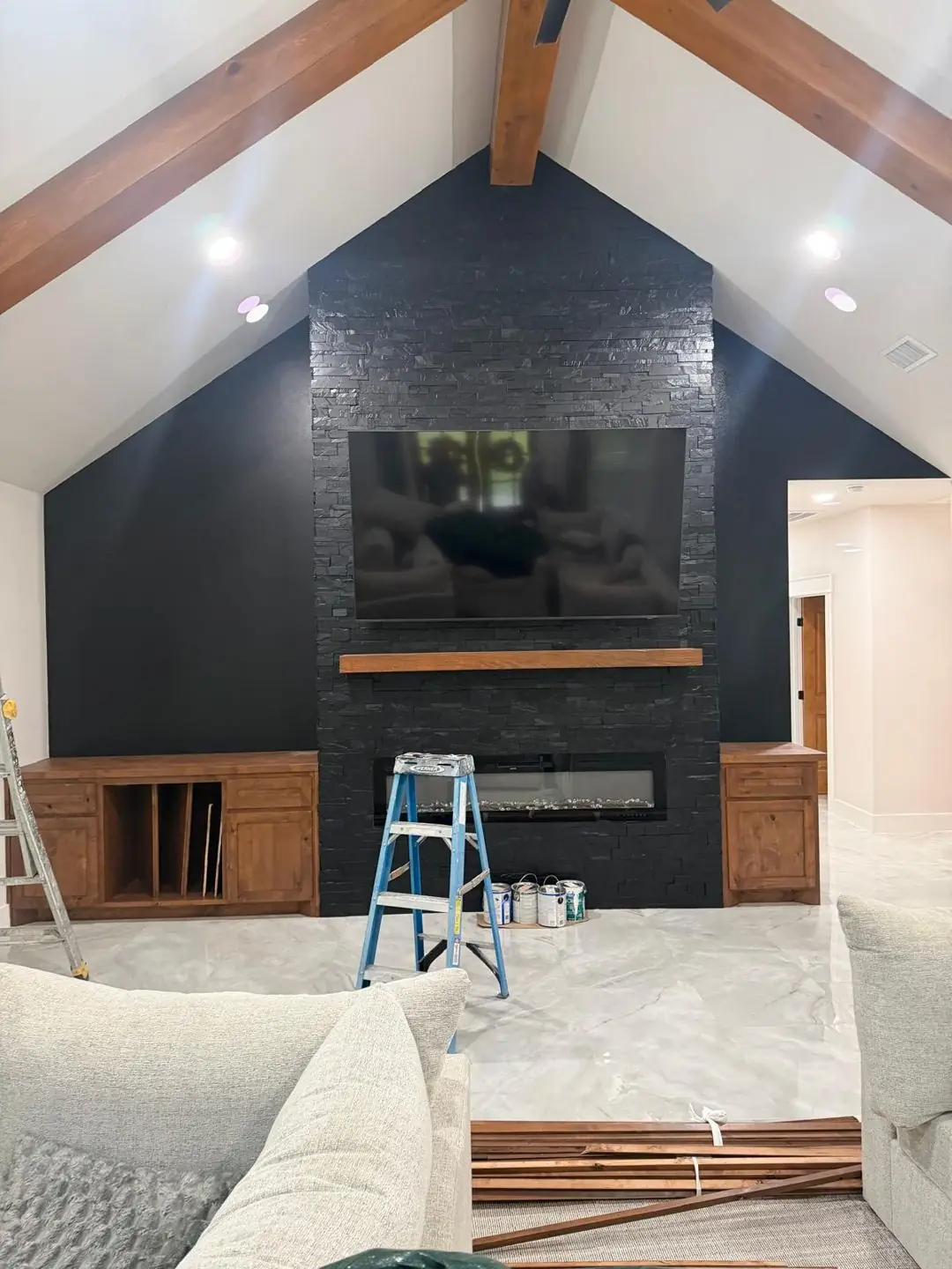 Finished living: dark stone fireplace wall, vaulted beams, TV