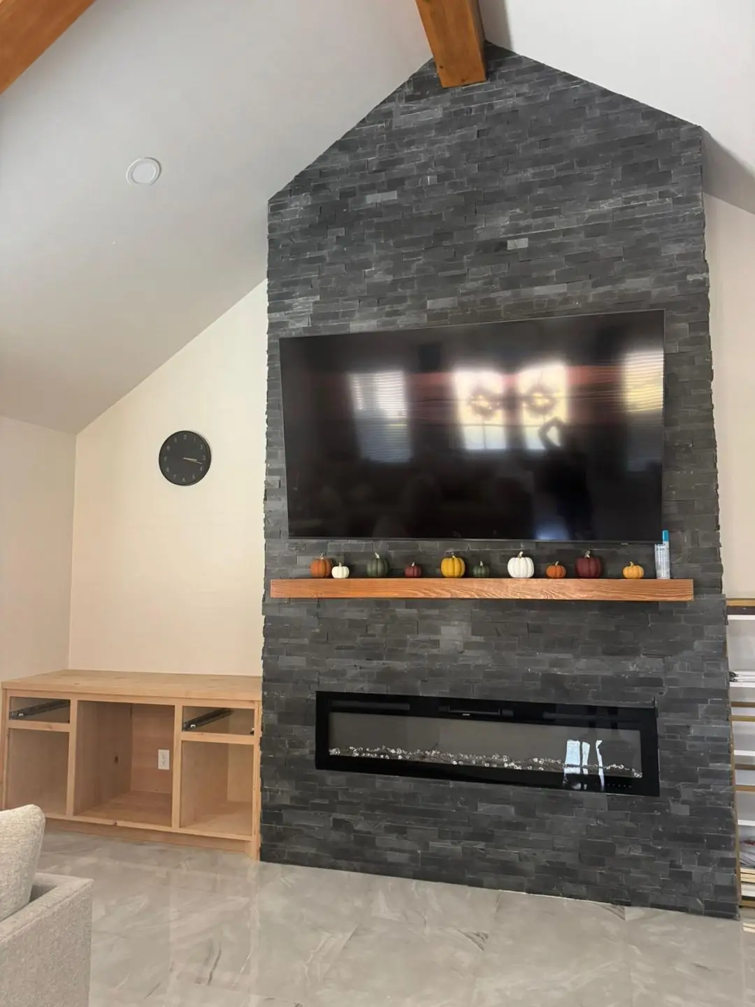 Finished living: dark stone fireplace wall, vaulted beams, TV