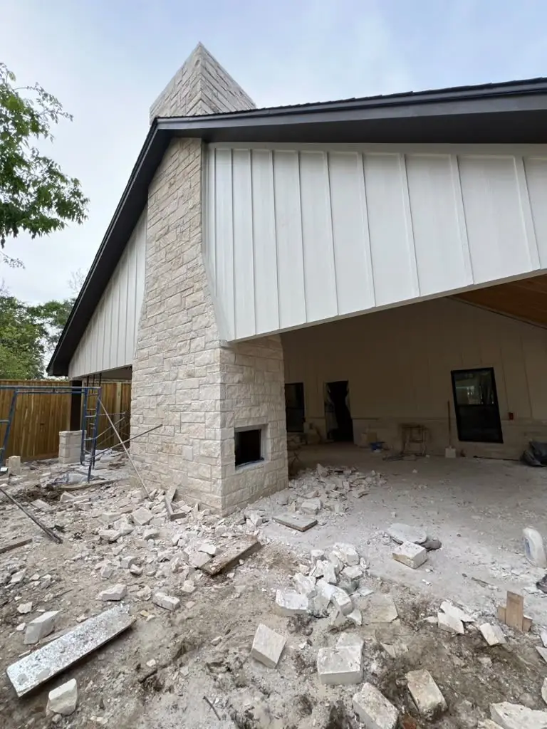 Stone fireplace + metal siding + covered patio under construction