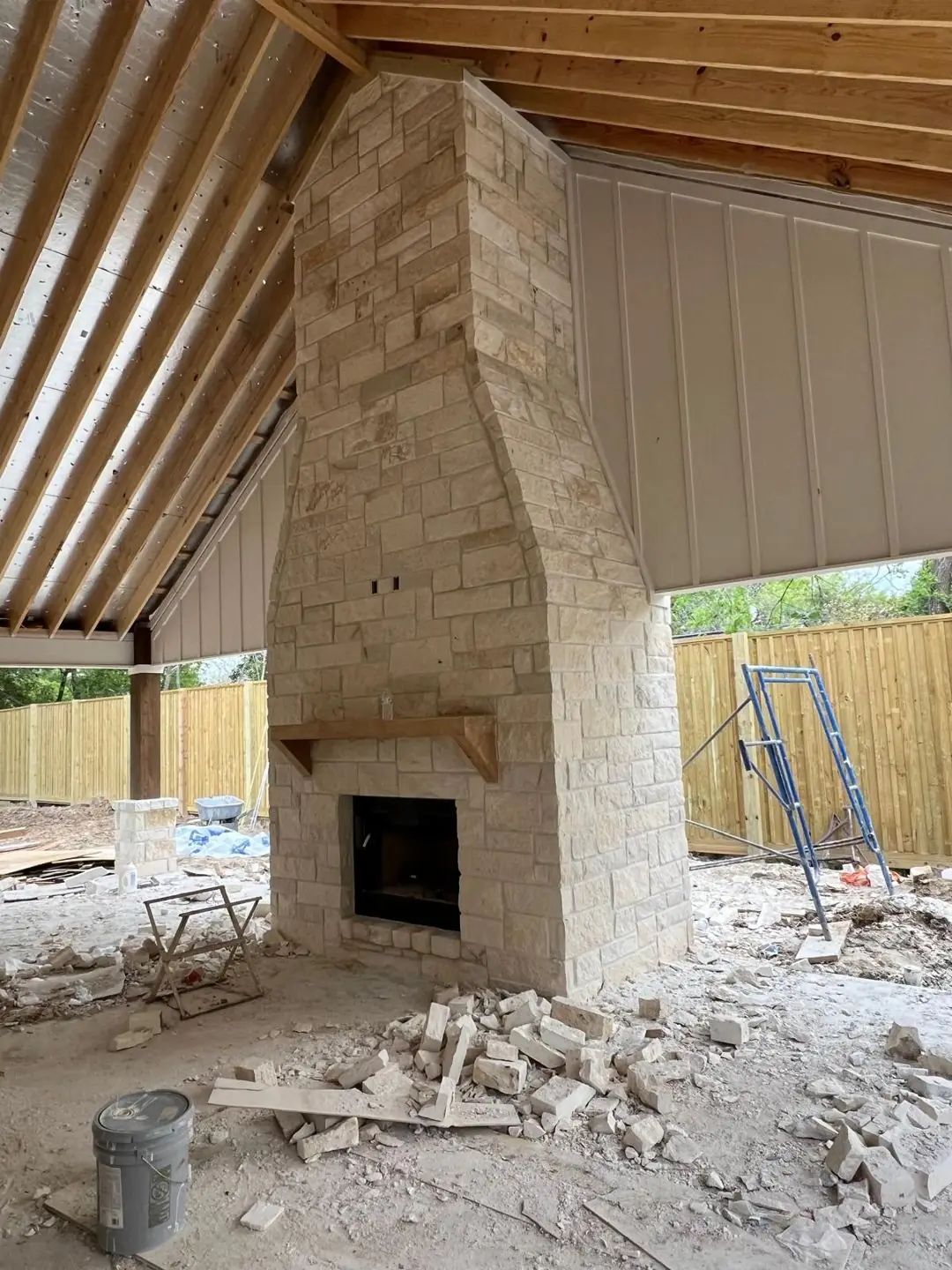 Stone fireplace + metal siding + covered patio under construction, Groves, TX