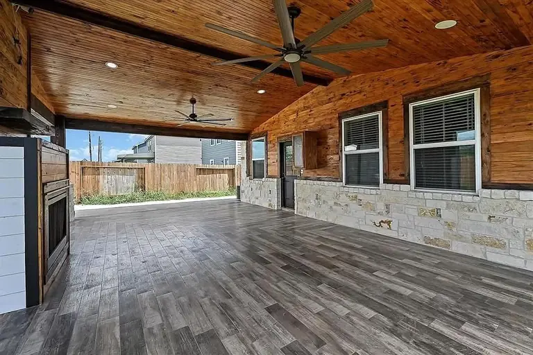 Covered rear patio, stained pine ceiling, stone, stamped concrete, detached garage