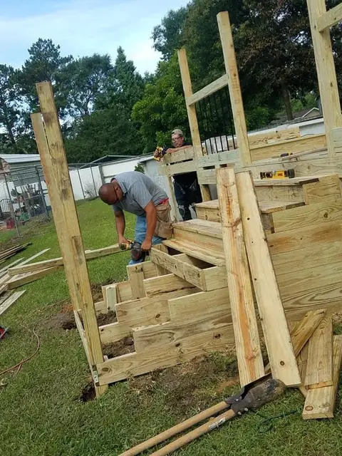 Above-ground pool deck stairs being built, worker bending over, Groves, TX