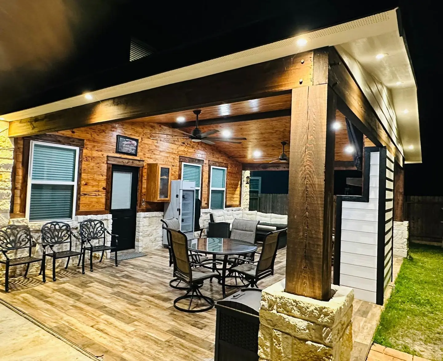 Covered patio at night: lit, dining set, stone column
