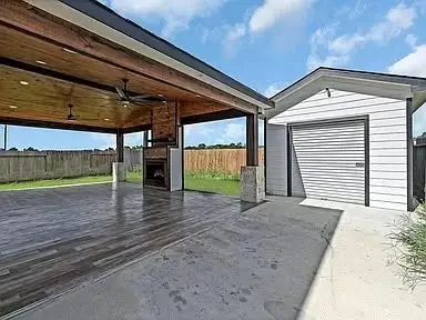 Covered patio with an outdoor fireplace next to a detached garage